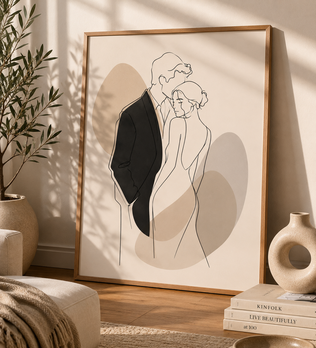 Quiet Embrace minimal line art print — large framed wall art of a couple in an intimate embrace with taupe shadow accents, leaning on a warm cream wall in a Scandinavian living room with olive tree and ceramic vases, Morphē Studio