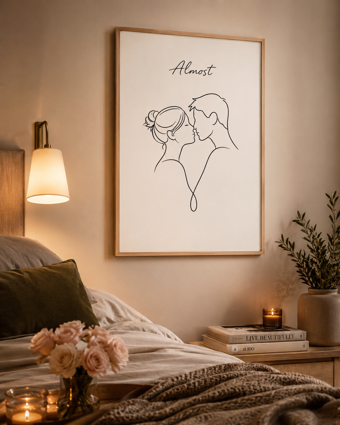The Almost Kiss minimal line art print — large framed wall art of a couple about to kiss with cursive Almost script, hung above a wooden nightstand with candle, stacked books and olive plant in a warm candlelit bedroom, Morphē Studio